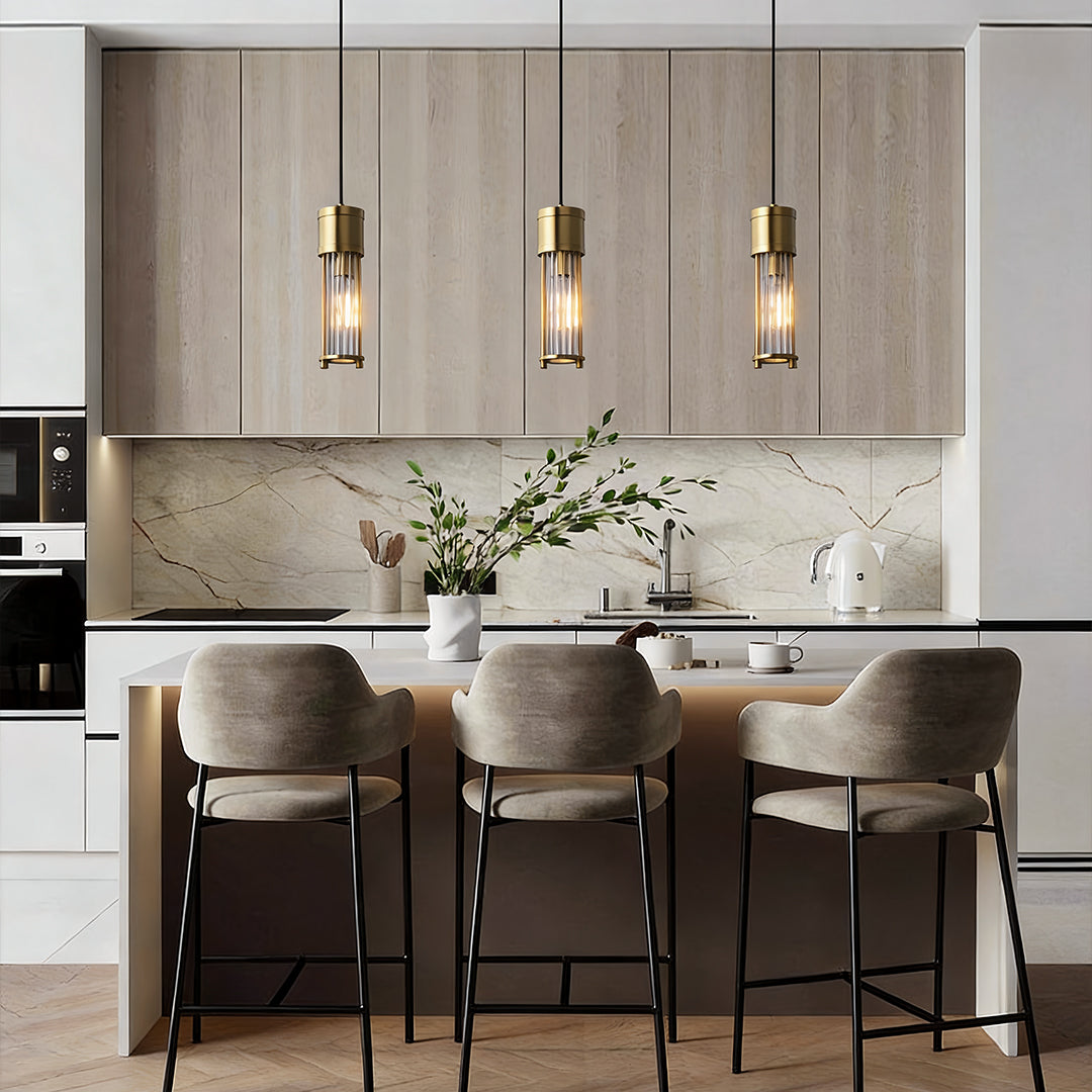 Gold cylinder pendant light installed above modern kitchen island.