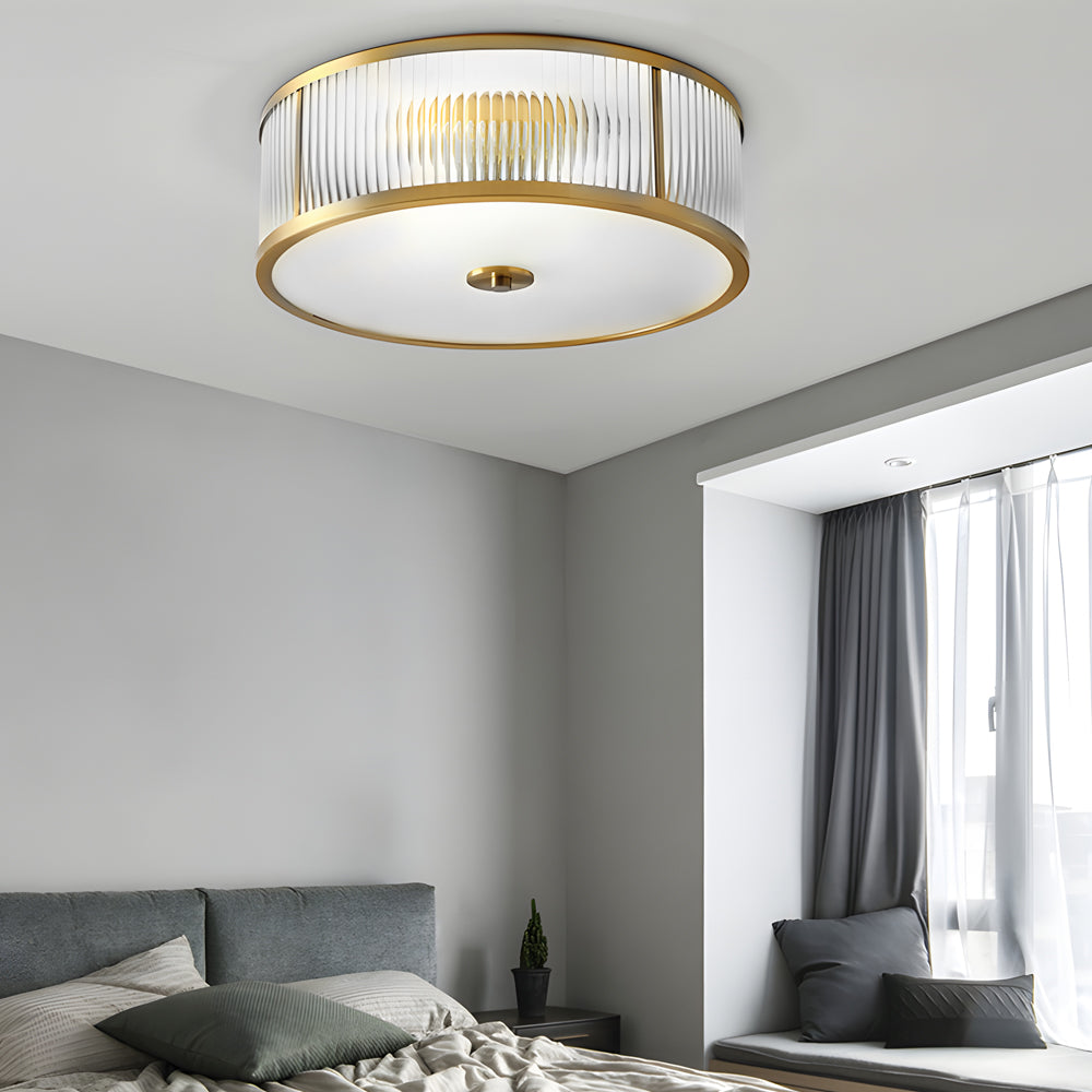 Gold drum ceiling light with a close-up of its detailed gold trim and light diffusion.