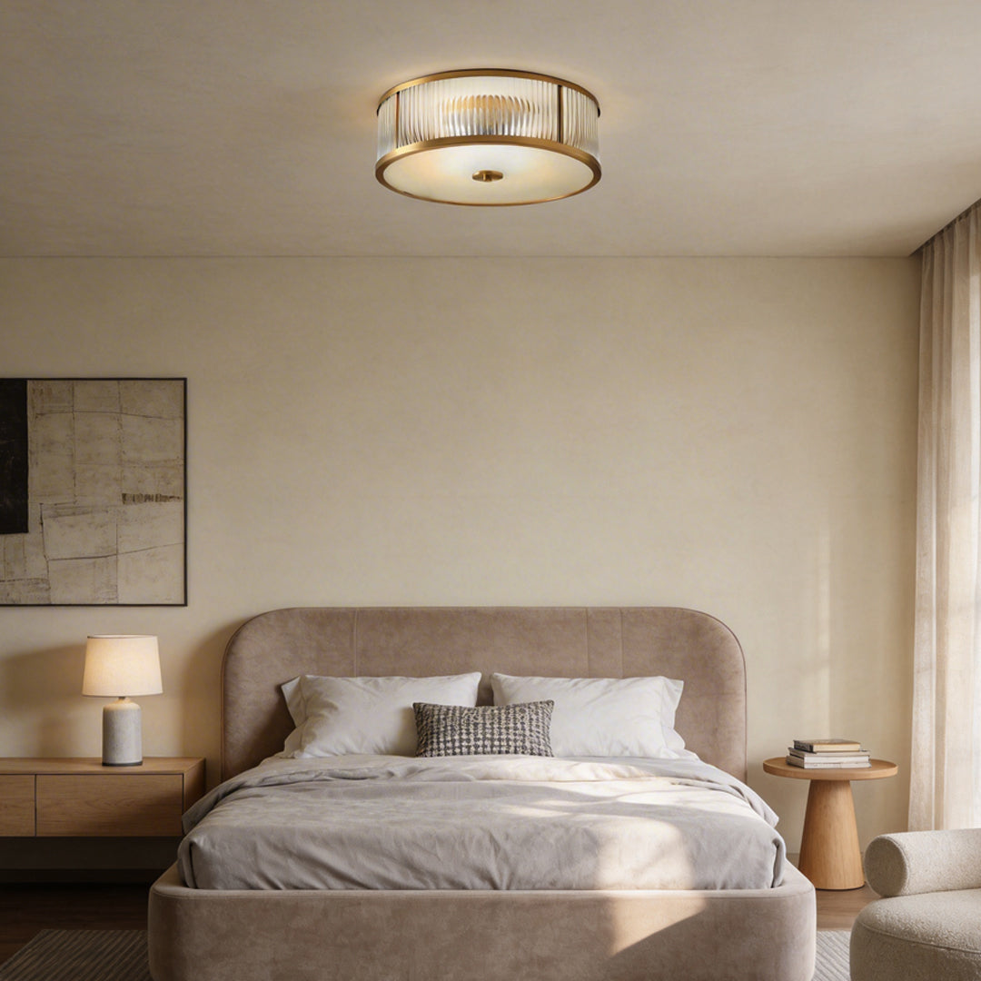 Gold drum ceiling light with a minimalist design, enhancing a cozy bedroom with soft light.