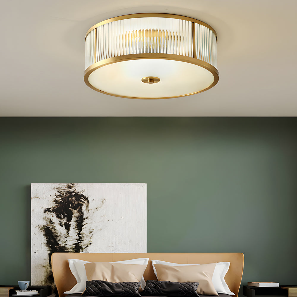 Gold drum ceiling light with a sleek gold finish, providing ambient light in a contemporary bedroom.