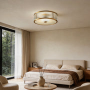 Gold drum ceiling light with a sleek design, providing warm illumination in a modern bedroom.