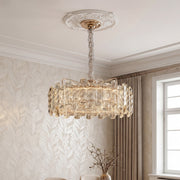 Luxurious gold nordic chandelier featuring a wide drum frame adorned with textured clear crystal prisms suspended in an elegant room.