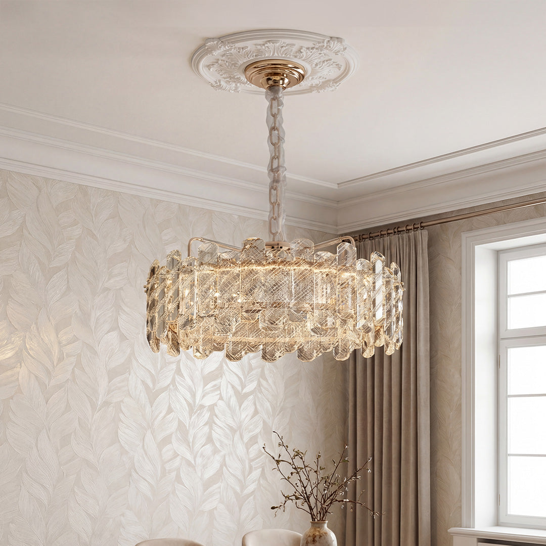 Luxurious gold nordic chandelier featuring a wide drum frame adorned with textured clear crystal prisms suspended in an elegant room.