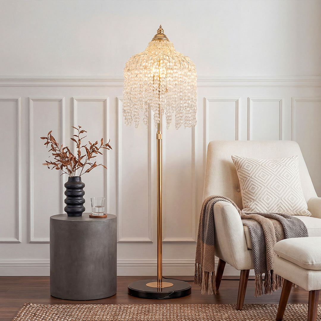 Elegant gold floor crystal lamps** with waterfall tassel shades beside a modern cream armchair.