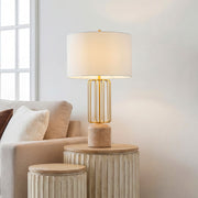 Gold geometric metal cage table light with a marble base and linen shade on a fluted wood table.