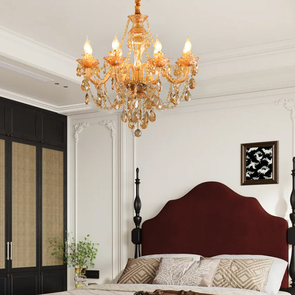 Gold glass candlelight chandelier hanging in a bedroom with a red headboard and classic wall detailing.
