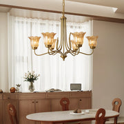 Gold glass chandelier installed in dining room with wooden furniture and neutral decor
