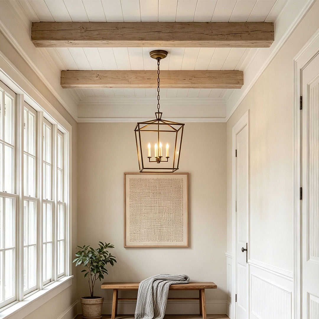 Gold lantern chandelier installed in a bright hallway with exposed wooden ceiling beams.