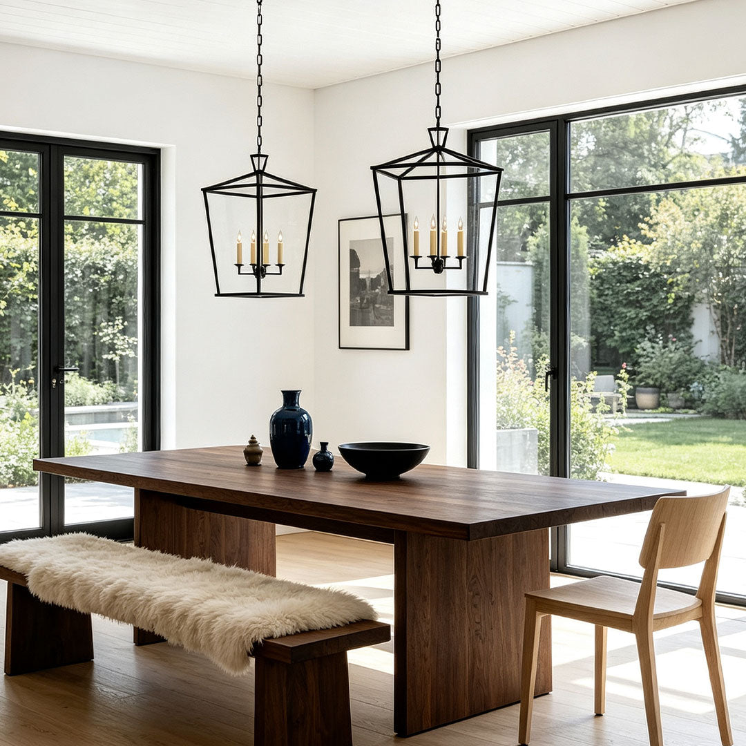 Gold lantern chandelier illuminating a modern dining room with large window views.
