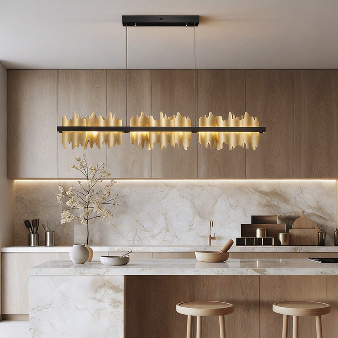 Gold linear pendant light with a sleek design, illuminating a modern kitchen island.