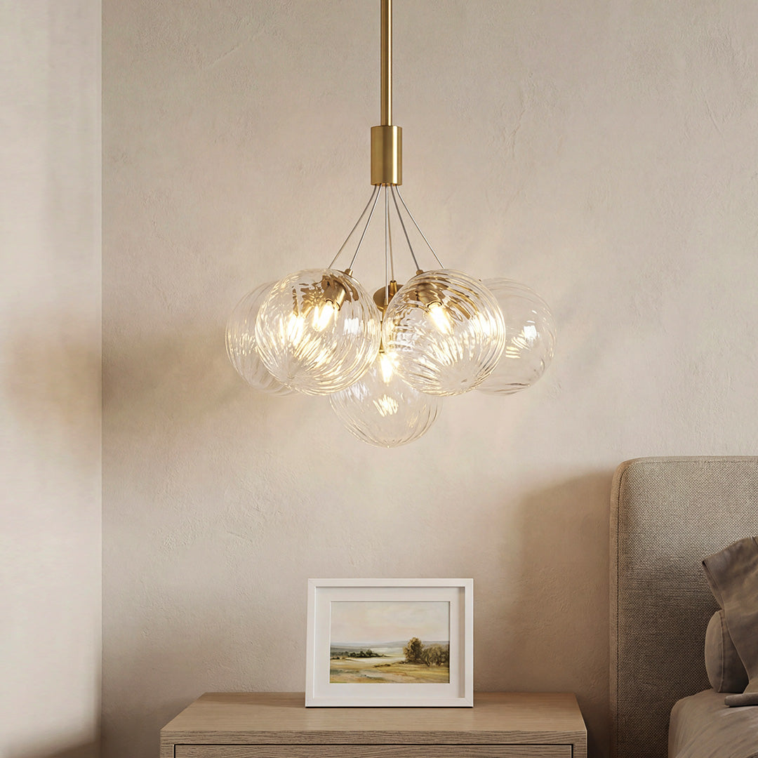 Elegant gold modern bubble chandelier featuring a cluster of textured clear glass globes illuminating a cozy bedroom setting.