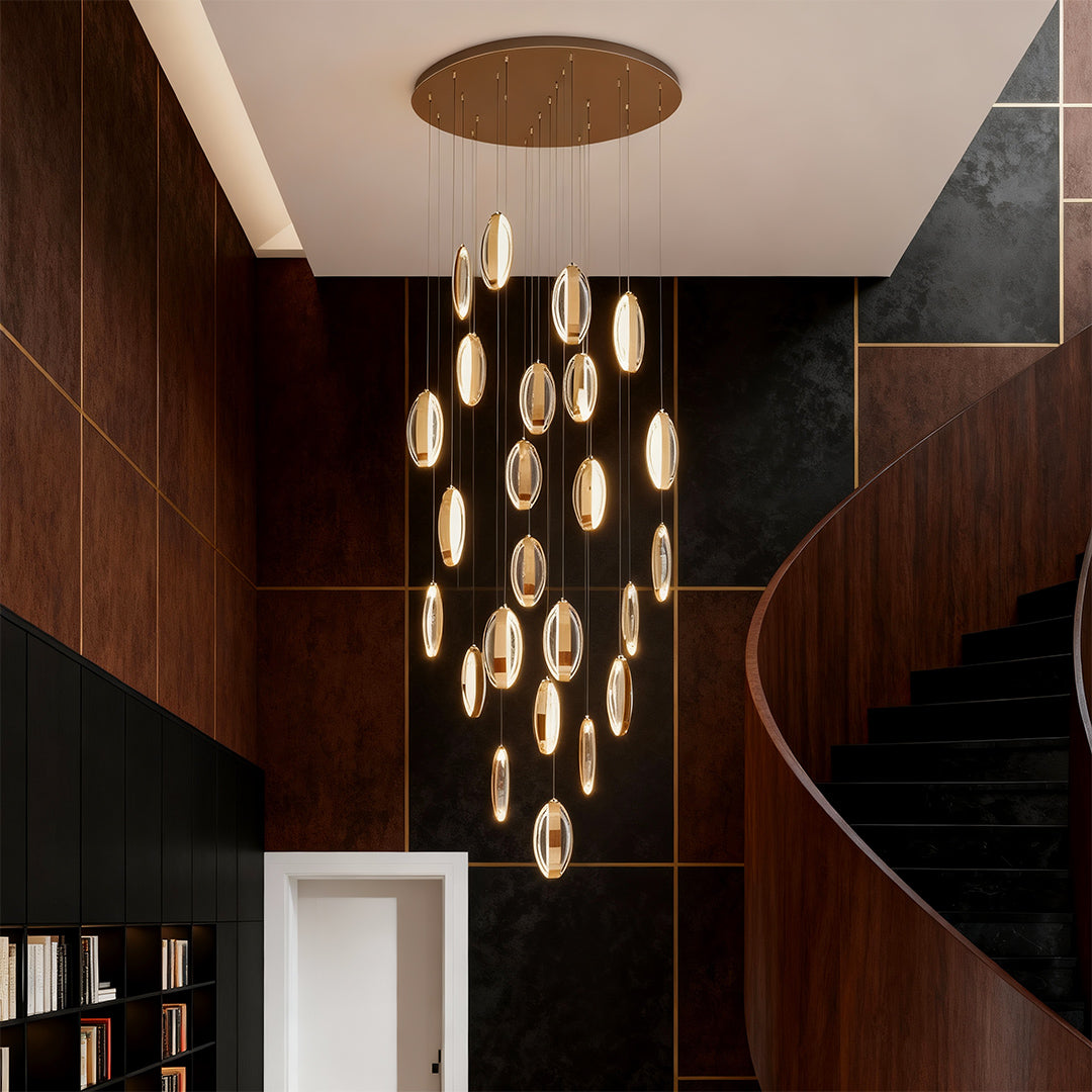 Gold modern chandelier creating sculptural focal point in curved stairwell with rich wood paneling and skylights