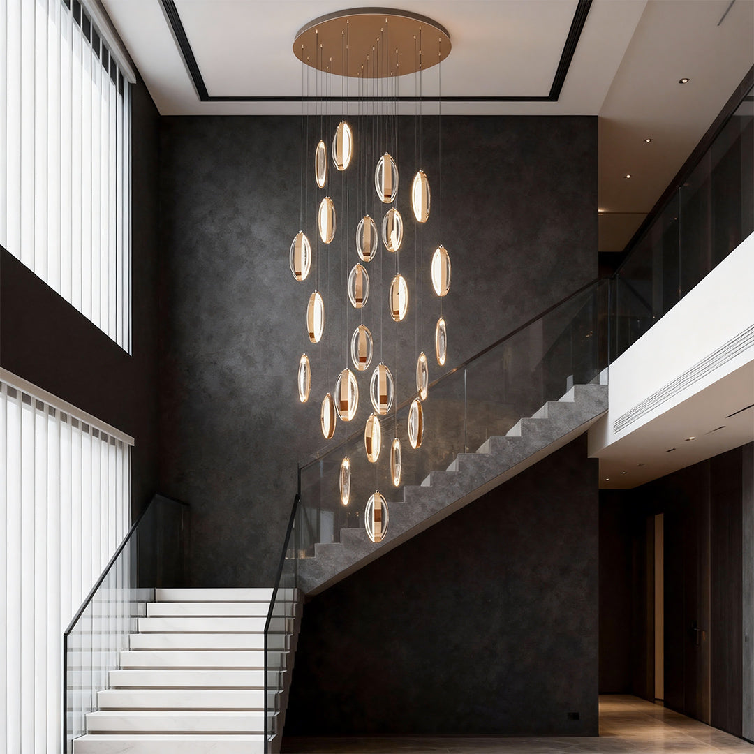 Gold modern chandelier illuminating dramatic double-height entryway with black walls and contemporary staircase design