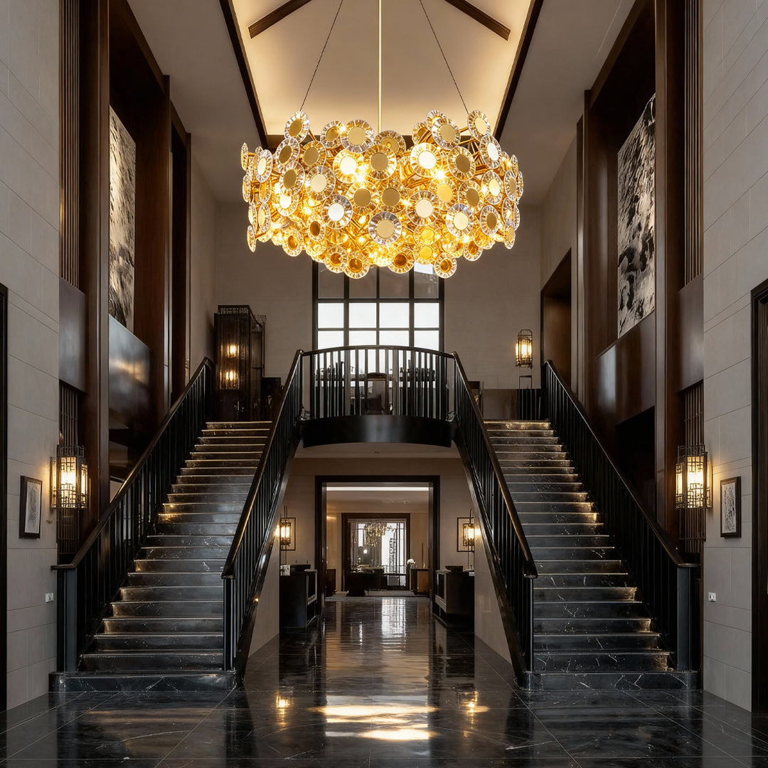 Gold modern chandelier creating dramatic focal point in grand entryway with dual staircases and dark wood paneling