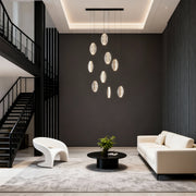 Gold modern chandelier providing artistic lighting in sophisticated living space with dark walls and contemporary furniture