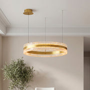 Elegant gold modern circular chandelier featuring a sleek ring design with textured crystal prisms suspended in a contemporary room.