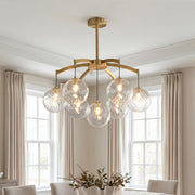 Elegant gold modern glass ball chandelier featuring textured clear glass globes suspended in a bright dining room.