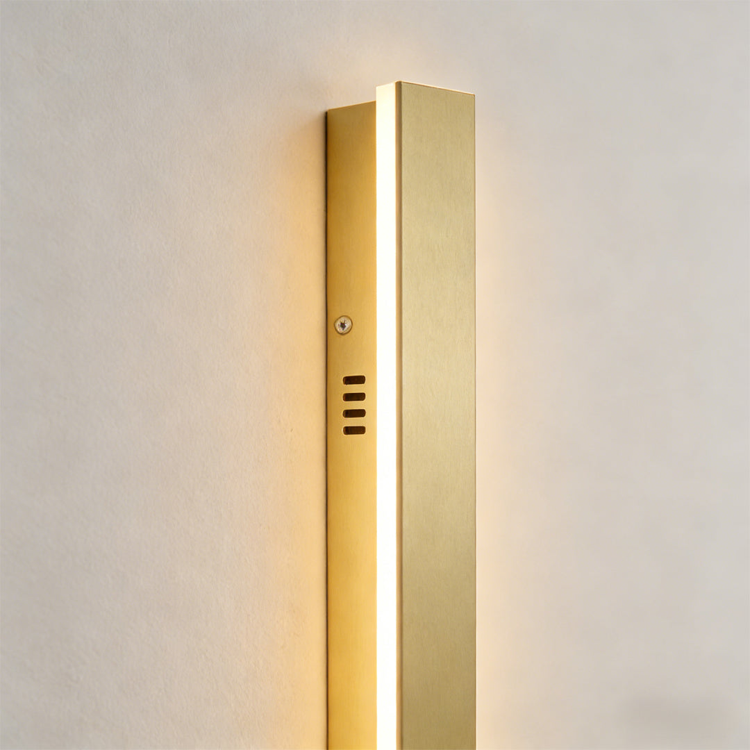 Gold outdoor wall light enhancing a contemporary building with vertical light.