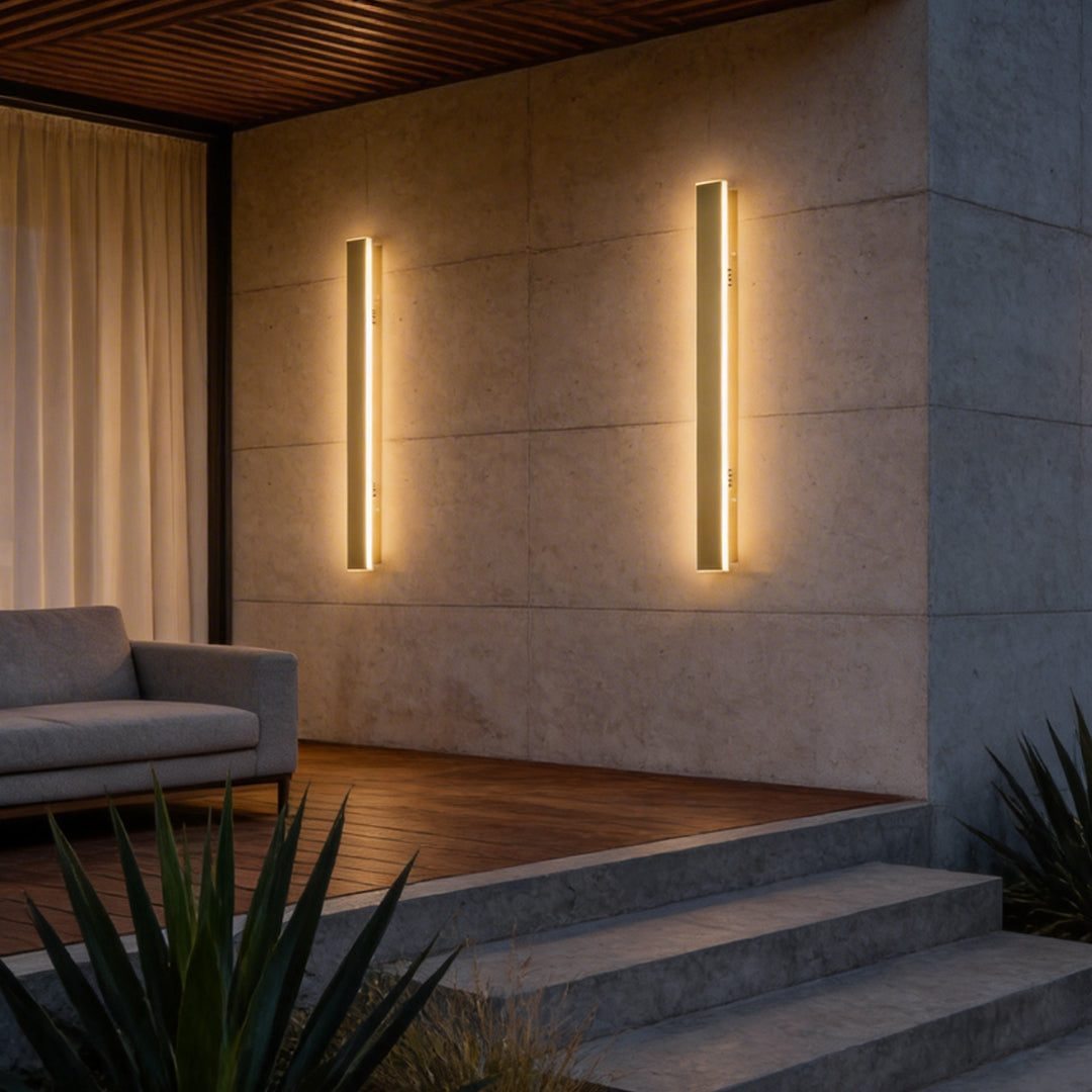 Gold outdoor wall light illuminating a modern exterior wall with vertical linear glow.