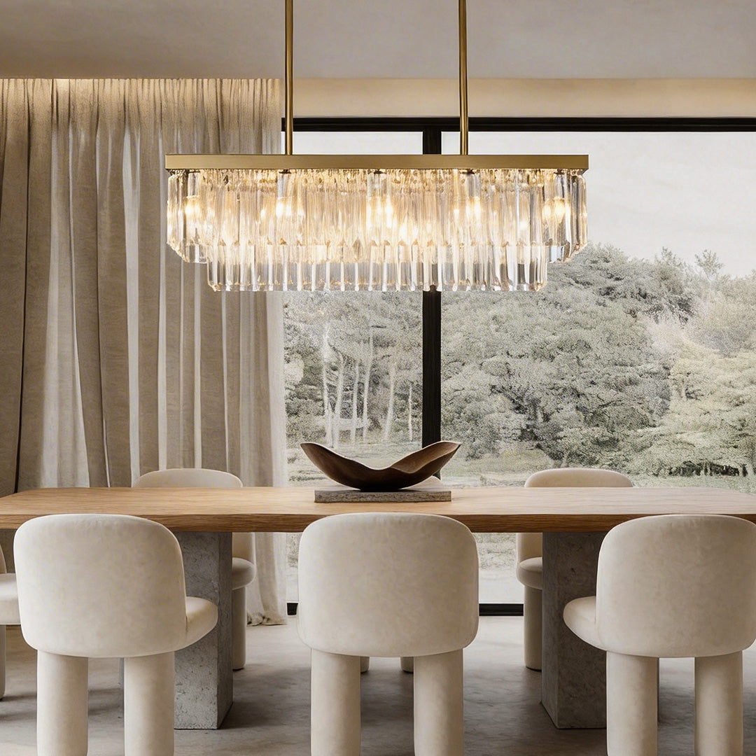 Gold rectangular chandelier with crystal droplets, illuminating a modern dining room.