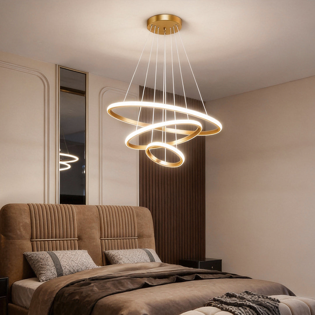 Gold ring LED chandelier hanging over a contemporary bedroom.