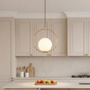 Elegant minimalist hanging lamp with a gold ring and glass globe over a modern kitchen island.