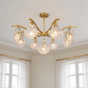Elegant gold shell chandelier light featuring curved brass arms and textured clear glass shades in a bright room.