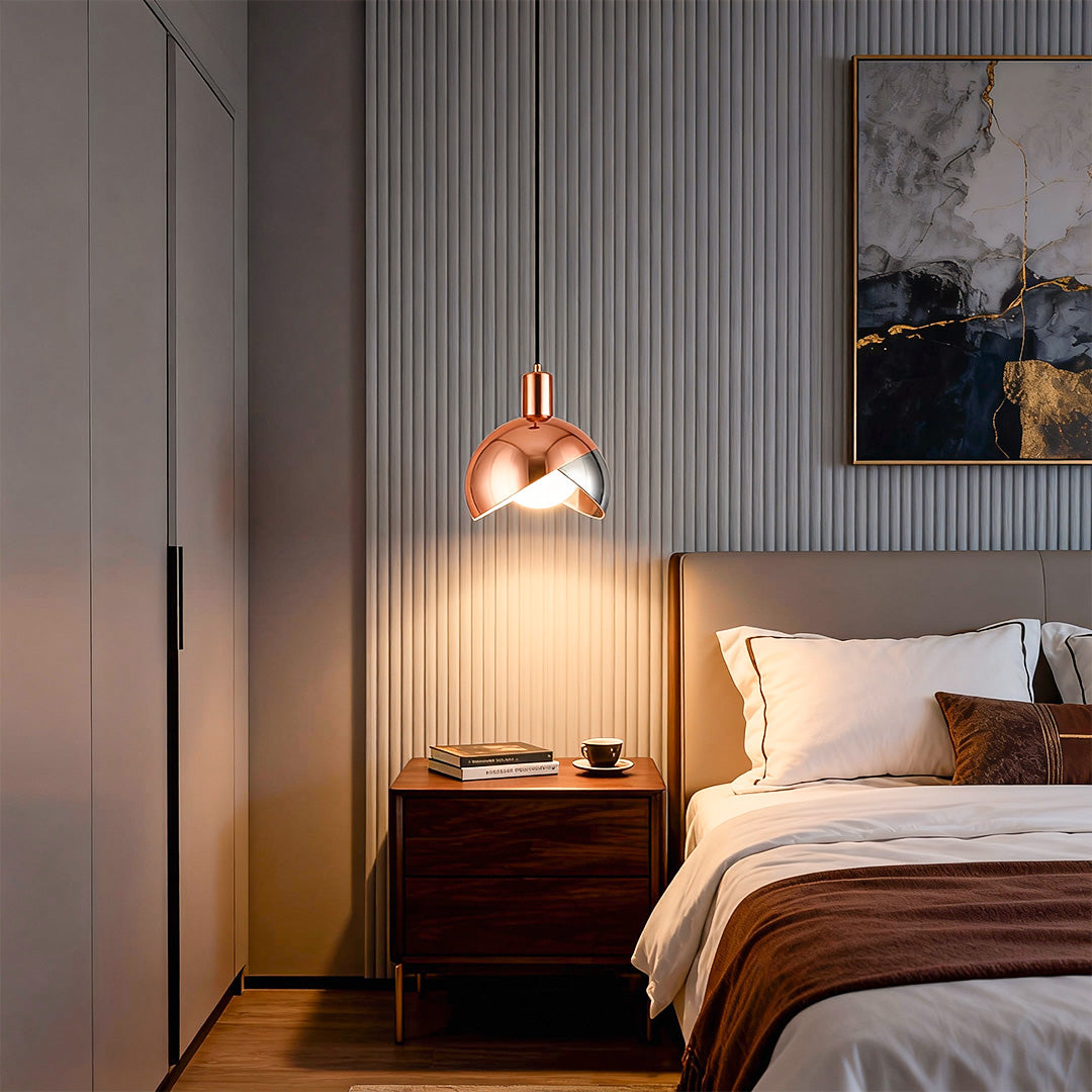 Gold sphere pendant light installed beside a modern bedroom nightstand, creating warm ambient lighting.