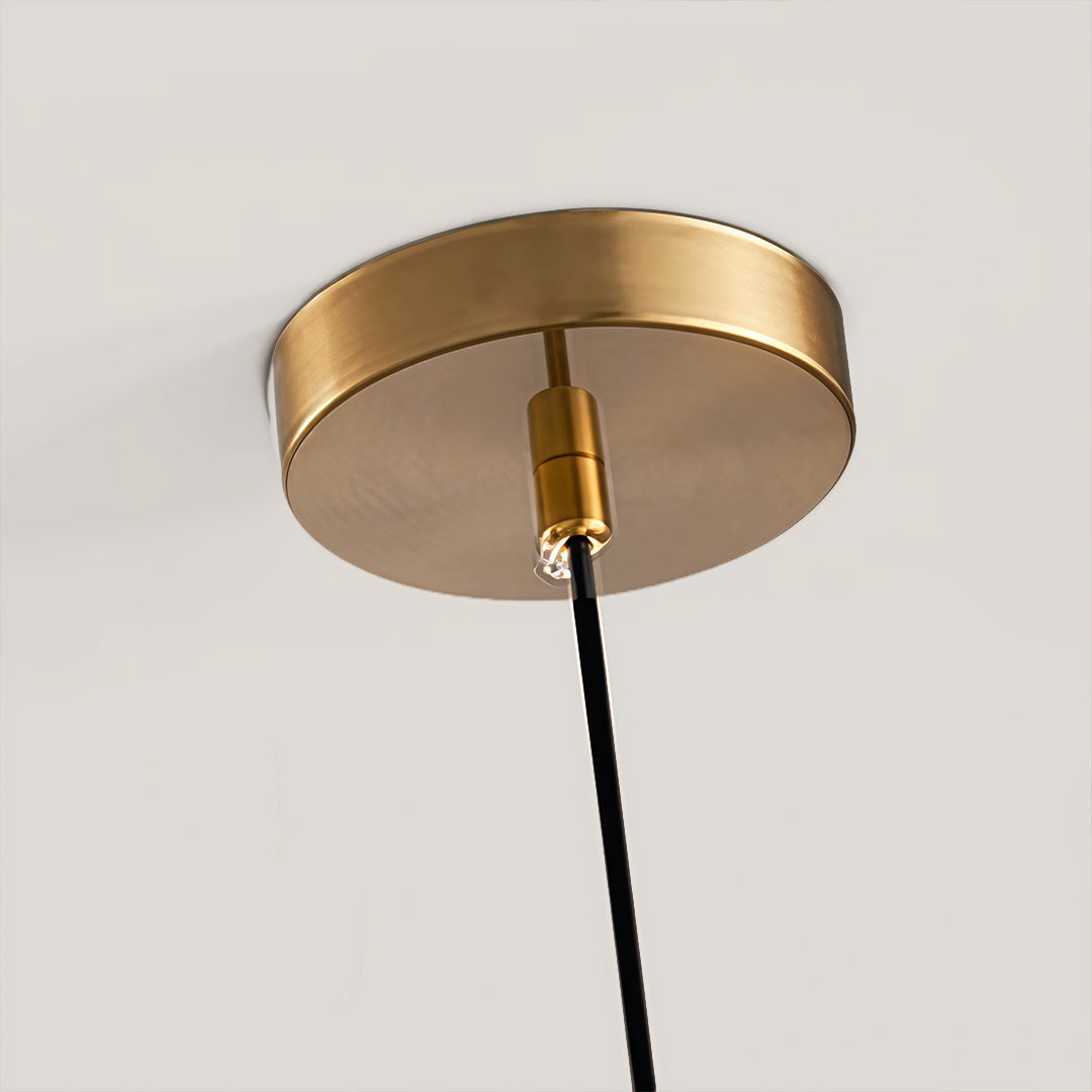 Ceiling canopy detail of gold sphere pendant light with clean round mounting plate.
