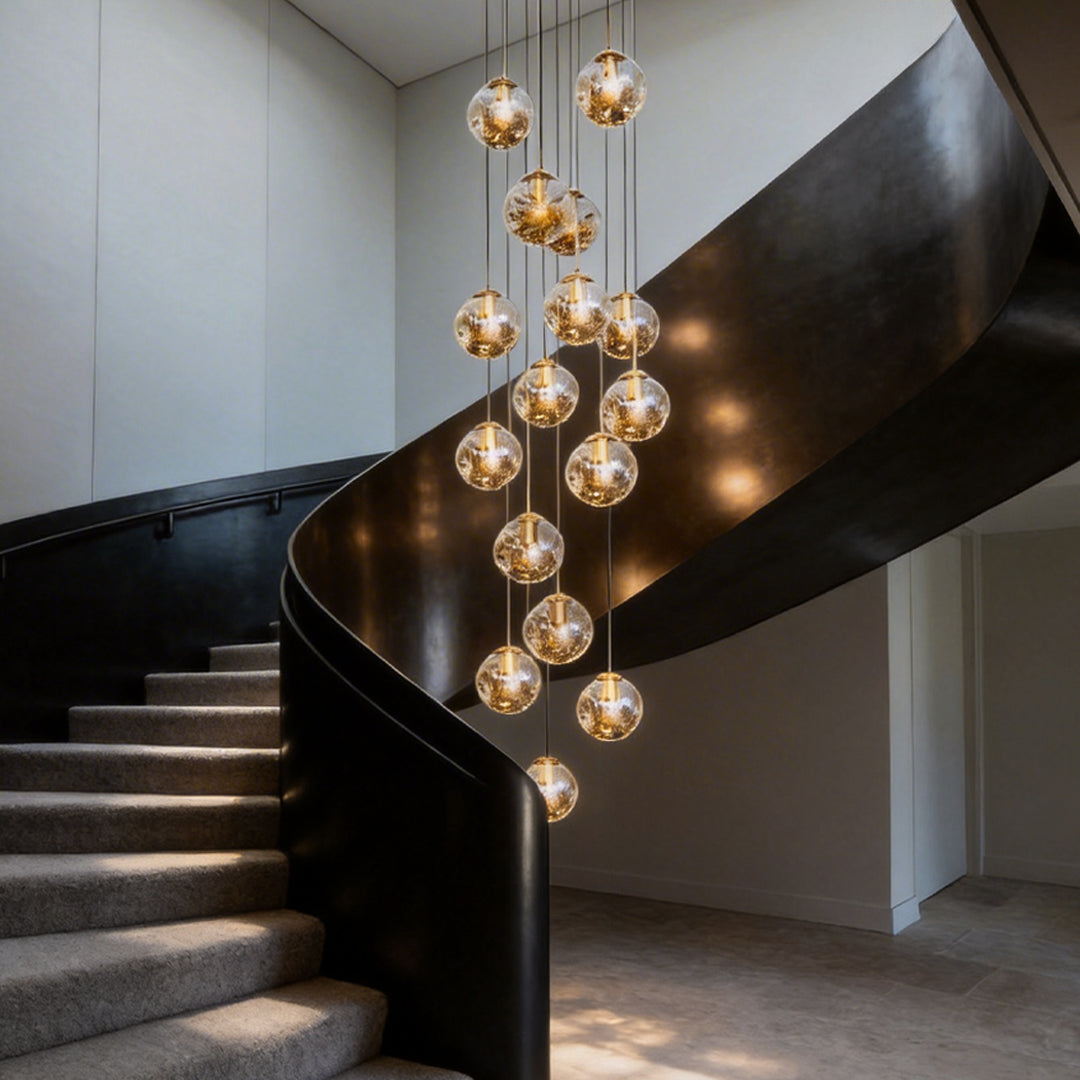 Gold staircase chandelier with multiple crystal globes, enhancing a contemporary black staircase.