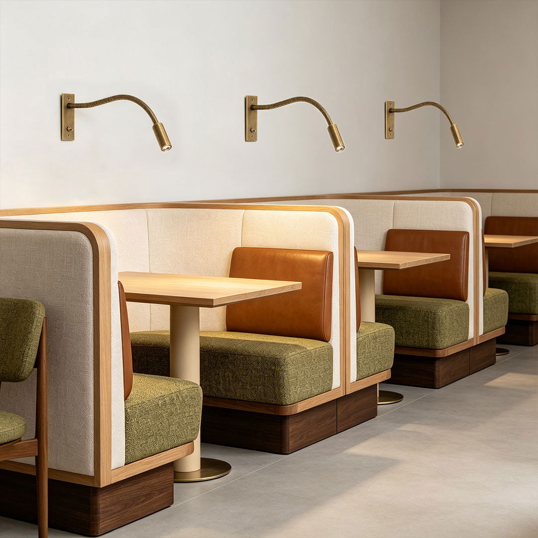 Gold swing arm wall mount lights installed above restaurant booth seating.