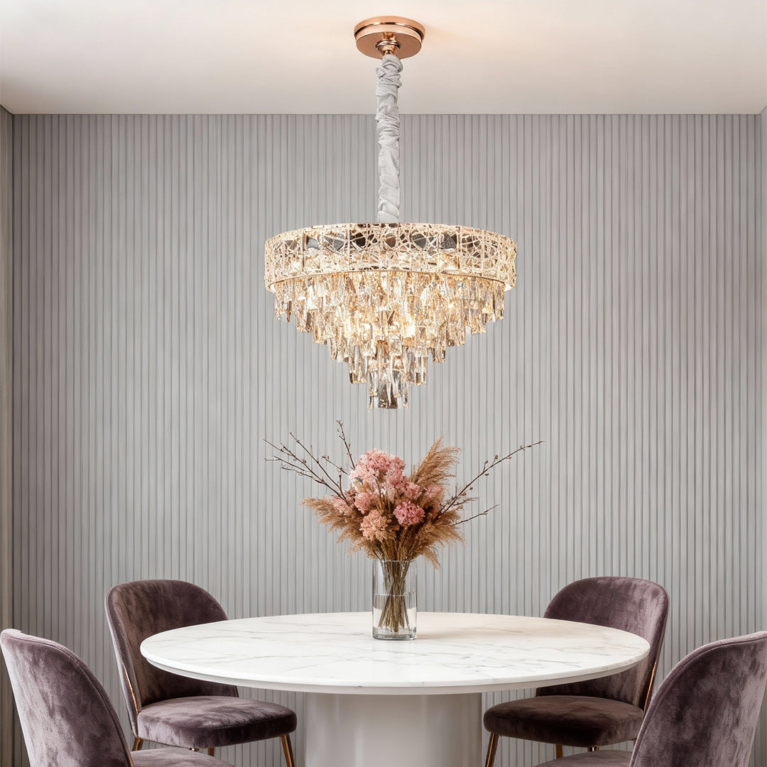 Gold tiered large chandelier crystals hanging above round marble dining table.