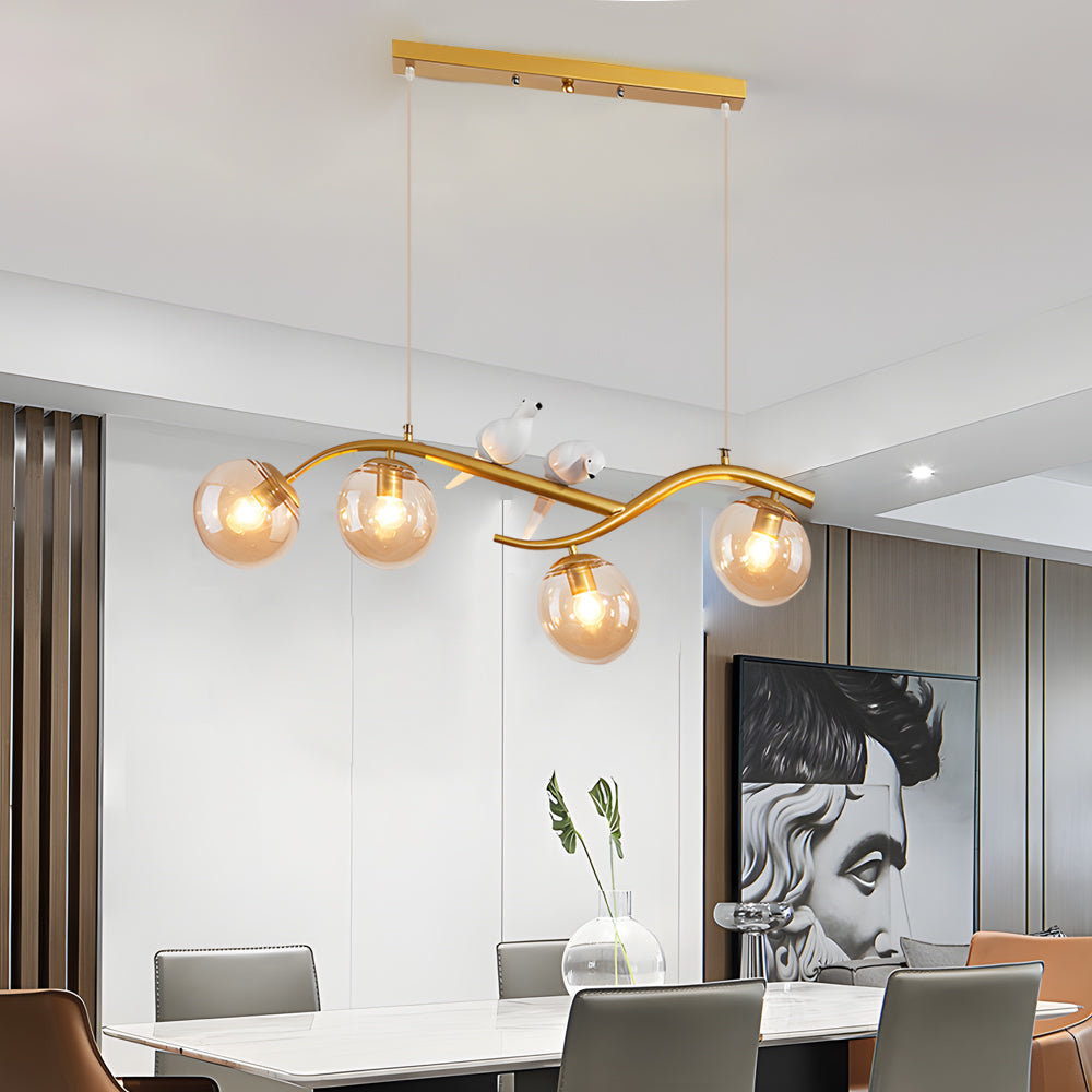 Gold tree branch pendant light hanging above modern dining area.