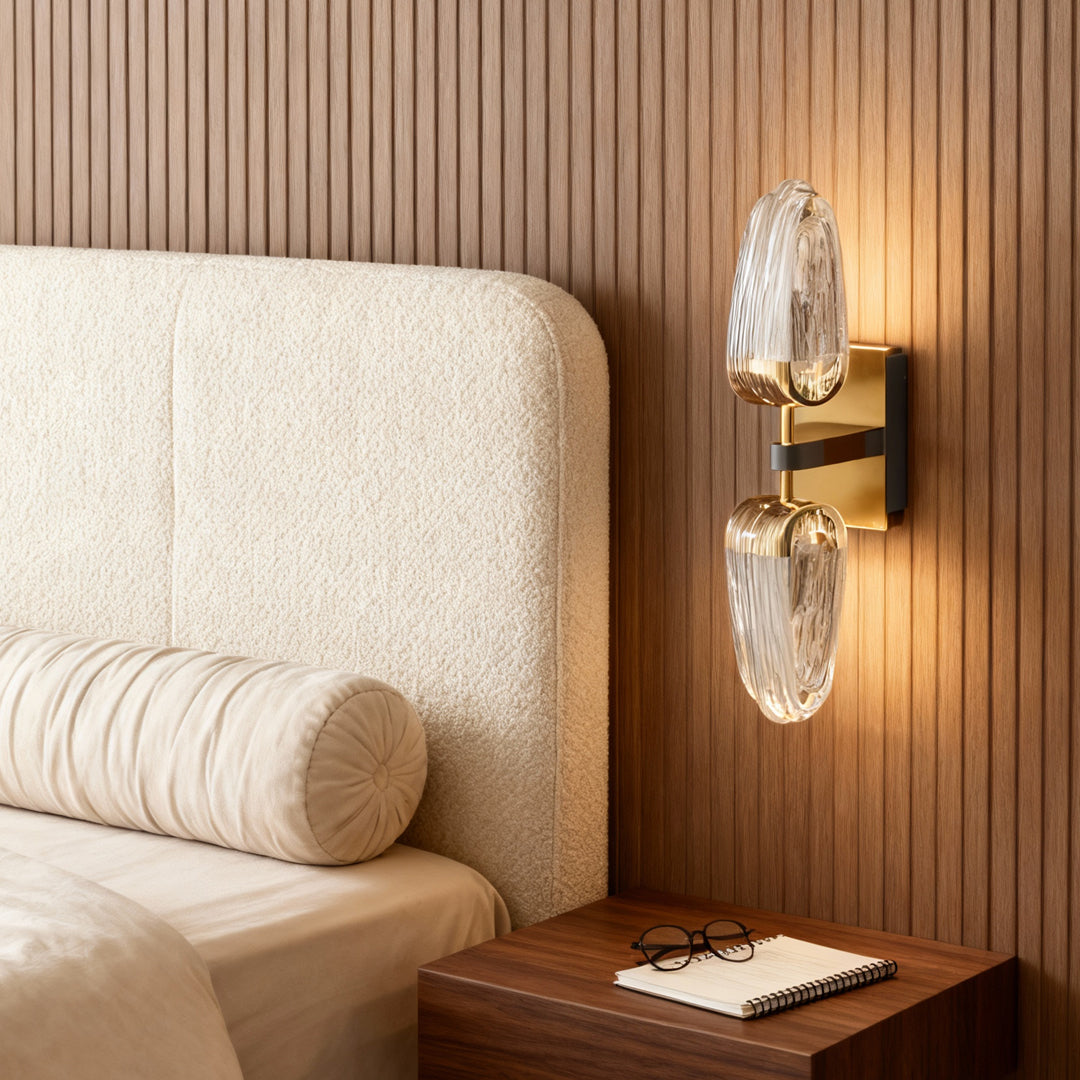 Gold wall light flanking bed in contemporary bedroom with vertical wood slat paneling and tufted headboard