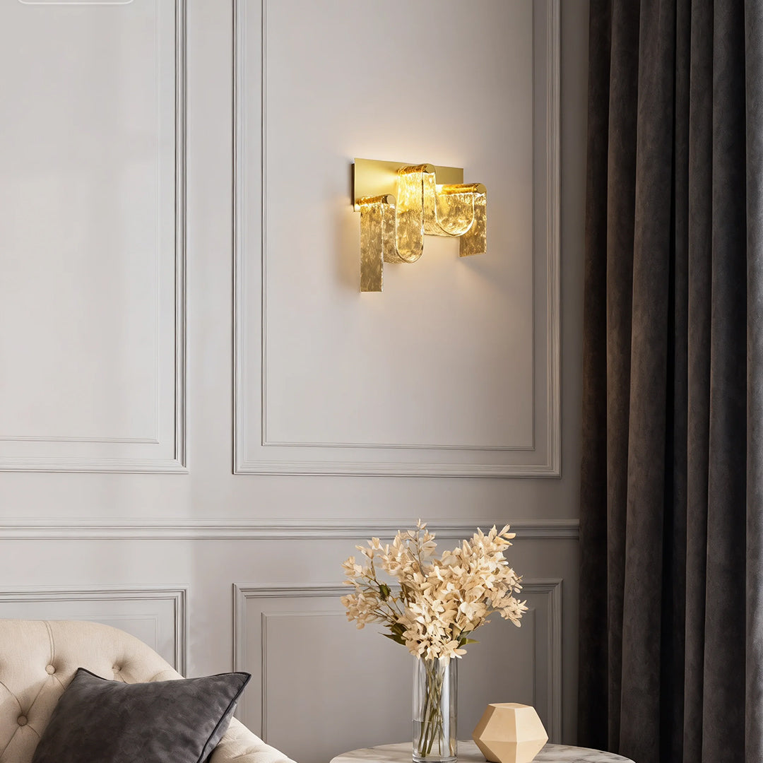 Gold wall light illuminating elegant living room with white paneling, grey curtains, and neutral decor