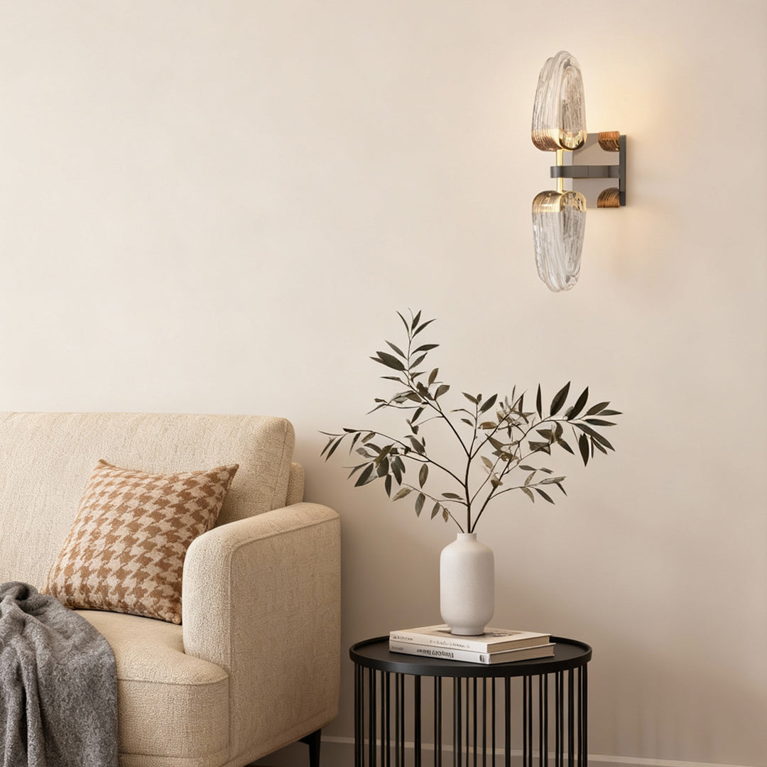 Gold wall light providing warm illumination in living room corner beside neutral sofa and botanical accent decor