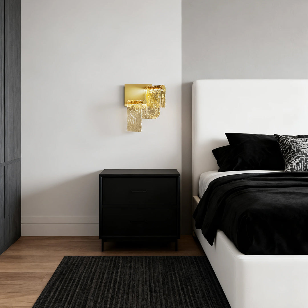 Gold wall light providing ambient lighting in modern bedroom with black platform bed and wood floors