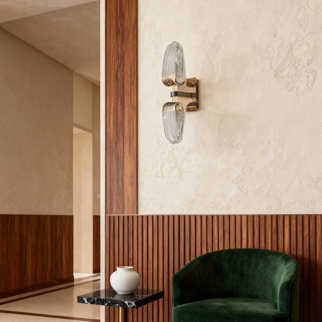 Gold wall light mounted in sophisticated living space with wood slat feature wall and emerald green velvet armchair