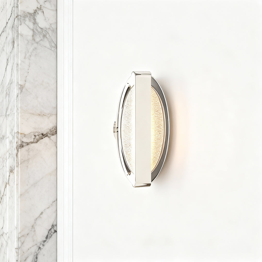 Gold wall lights creating sophisticated glow on textured wall beside decorative marble accent panel