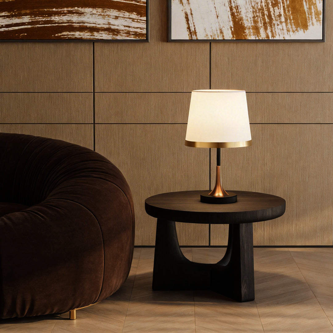 Gold white table lamp with a white shade, providing warm light on a modern side table.