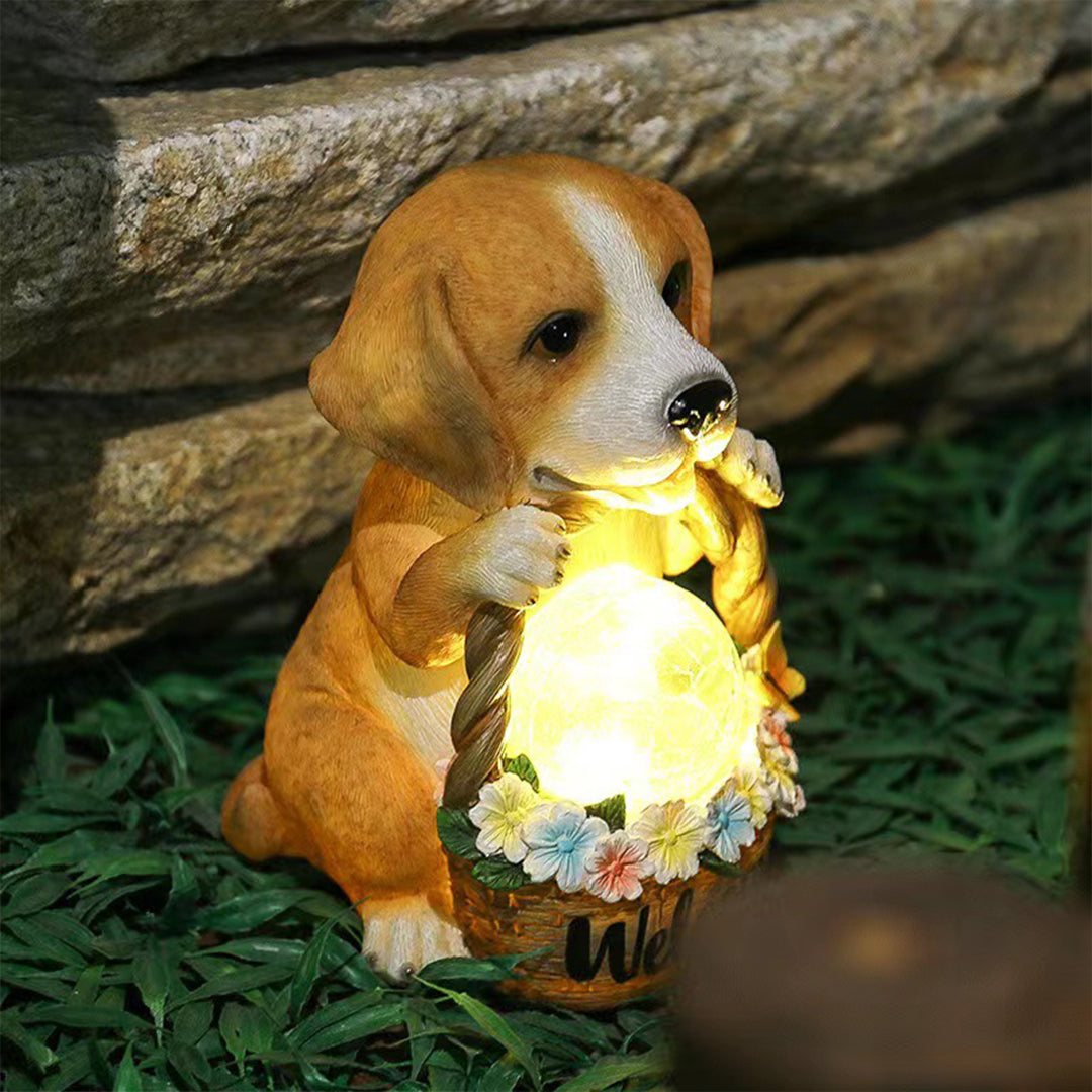 Golden puppy statue with illuminated welcome basket creating magical lighting among garden plants