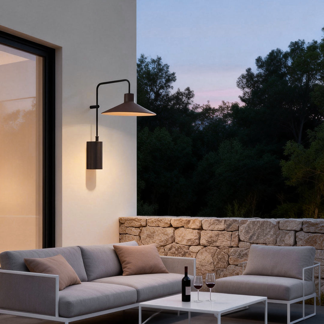 Gooseneck wall lamp installed above an outdoor patio seating area, creating a cozy and inviting evening atmosphere.