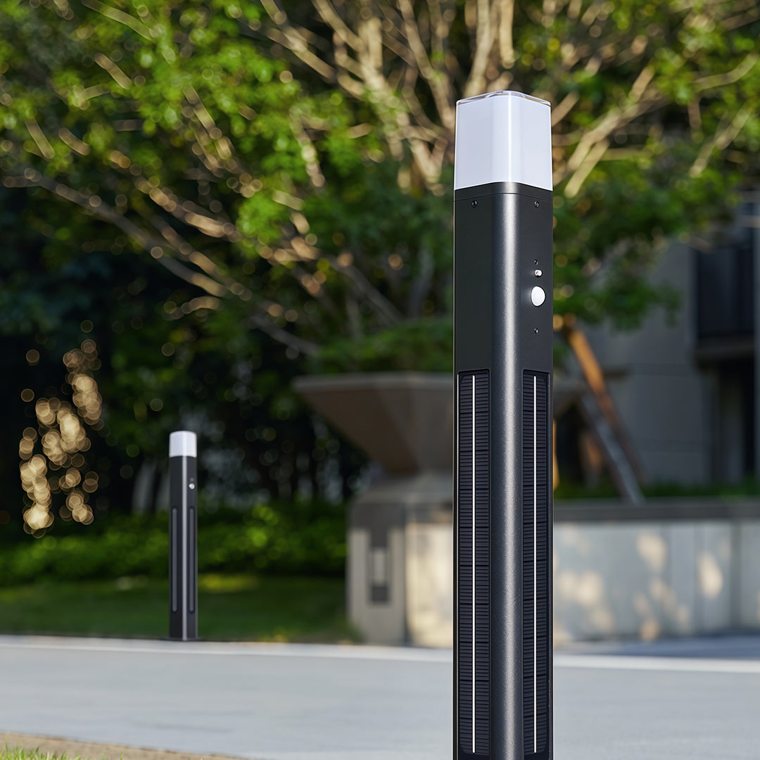 Solar bollard lighting in black, mounted beside a gravel path, enhancing nighttime visibility.