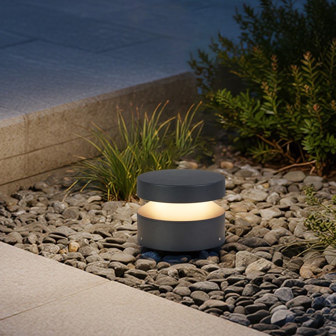 110v landscape light creating warm glow on gravel surface beside concrete walkway in evening setting