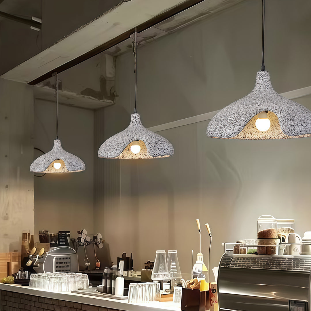 Gray Cement Pendant Lights illuminating modern café interior with wooden tables and warm tone.