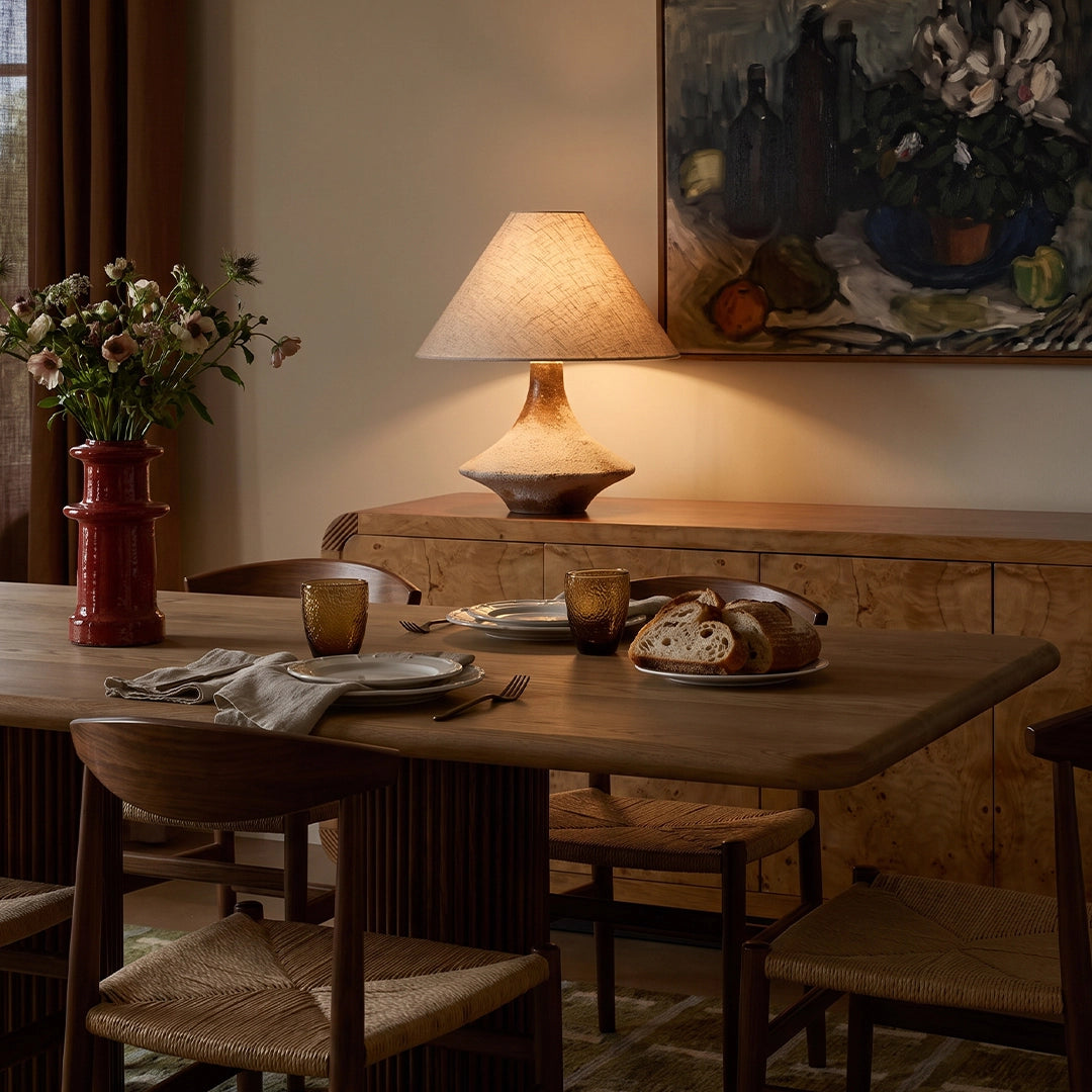 Gray ceramic table lamp placed on a wooden dining table, adding warm ambient light to a cozy traditional dining room.