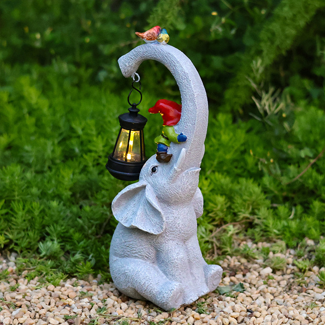 Gray elephant garden statue with red flowers and hanging black lantern in outdoor garden setting