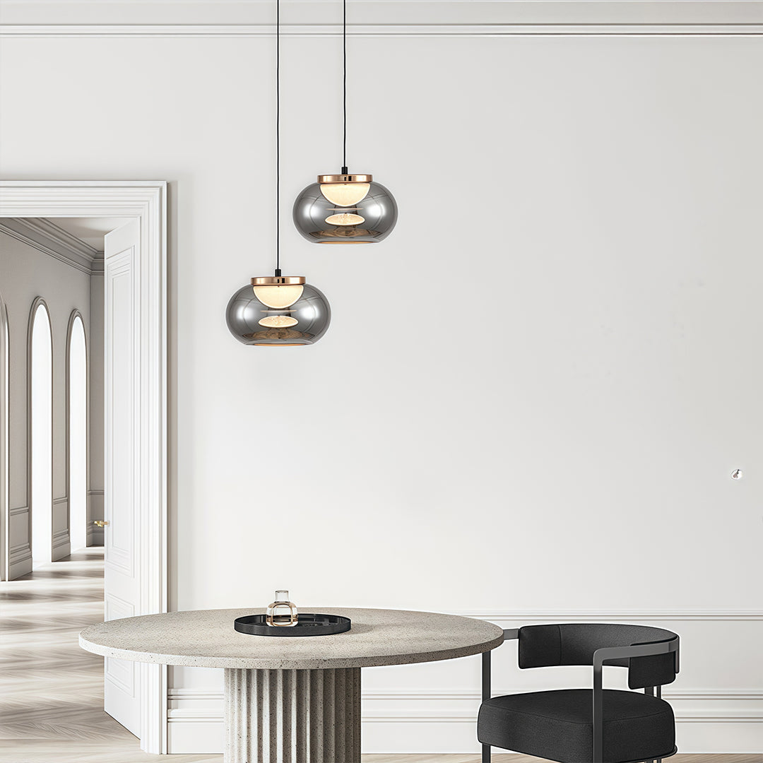 Gray glass pendant light brightening contemporary dining space with white furniture and neutral decor.