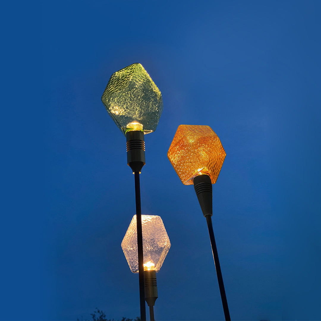 Green and amber glowing pathway globes installed among plants, enhancing night landscape lighting pathway effects.