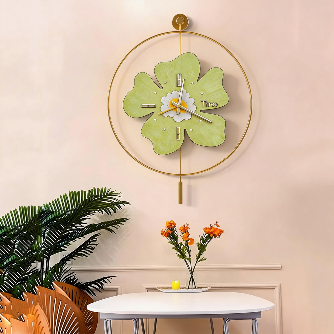 Decorative green floral wall clock with light and pendulum above a white dining table.